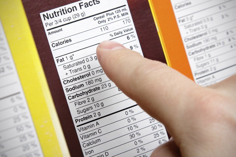 A concerned shopper checks the nutrition labels of various boxes of cereal.